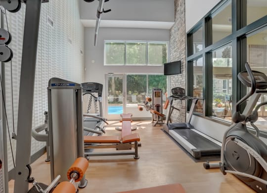 Gym with exercise equipment and a large window with a pool in the background at Governor's Park, Fort Collins, 80525