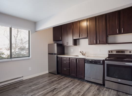 Empty kitchen with wooden cabinets and stainless steel appliances and a window  at Governor's Park, Fort Collins, 80525